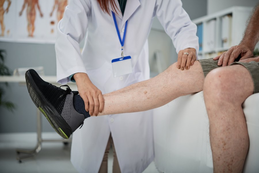 Fisioterapeuta examinando perna de homem.