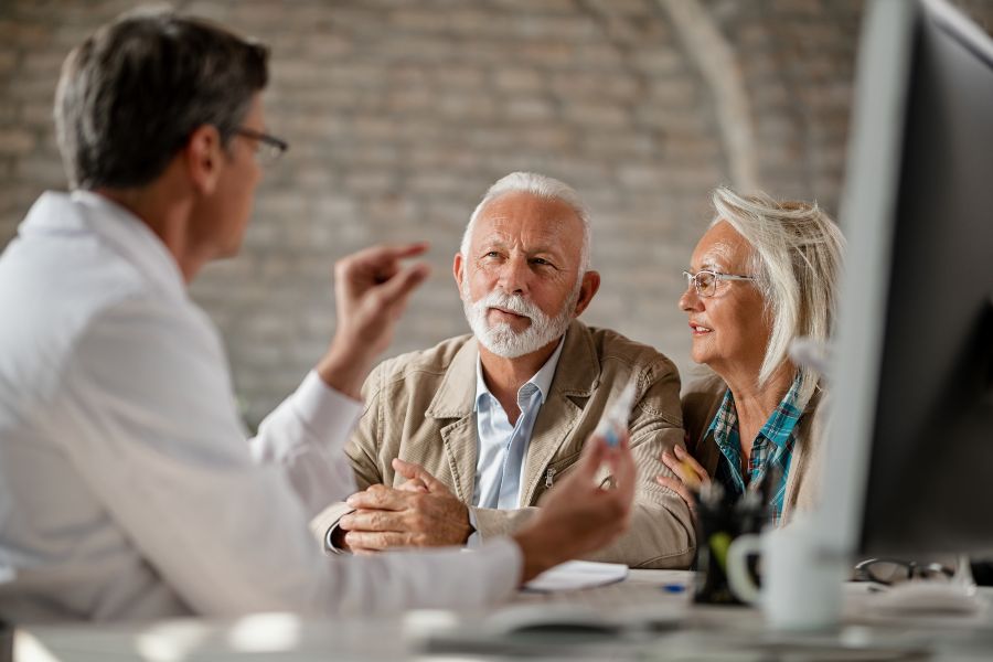 Médico conversando com casal de idosos.