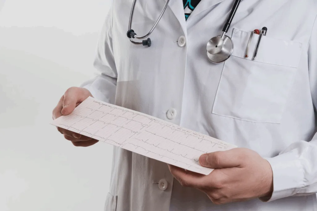 Médico de jaleco e estetoscópio segurando o traçado impresso de um eletrocardiograma